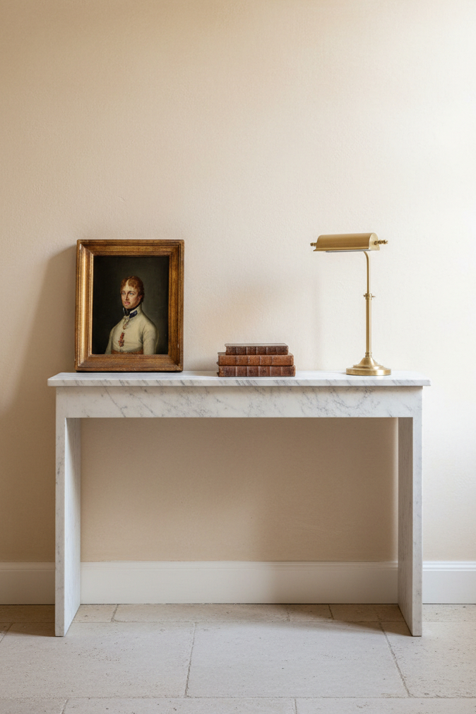 The small portrait propped against a pale wall on a marble console, shown to scale beside a stack of old books and a brass lamp (young Austrian officer, early 19th century oil on canvas)