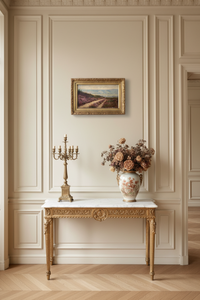 The framed heather landscape hung above a marble topped giltwood console in a panelled entrance hall, dried flowers and a candelabrum below (Desvarreux heather path)