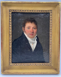 Young man in a dark coat and high white cravat against a grey ground, small early nineteenth century French oil portrait in its original gilt bead frame