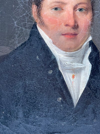 The sitter's bust with the dark coat and its metal buttons, the red rosette on the white waistcoat, and small paint losses across the coat
