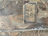 A small printed label on the frame with a blue ruled border, carrying two handwritten numbers in ink