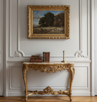 Room view mockup showing the framed landscape on a white panelled wall above a gilt console with a marble top and a stack of books