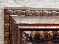 Close view of the frame corner showing the outer run of beads, the tight mitre, and dust settled in the carving