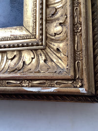Corner of the gilt frame showing the carved foliate ornament and the bead course