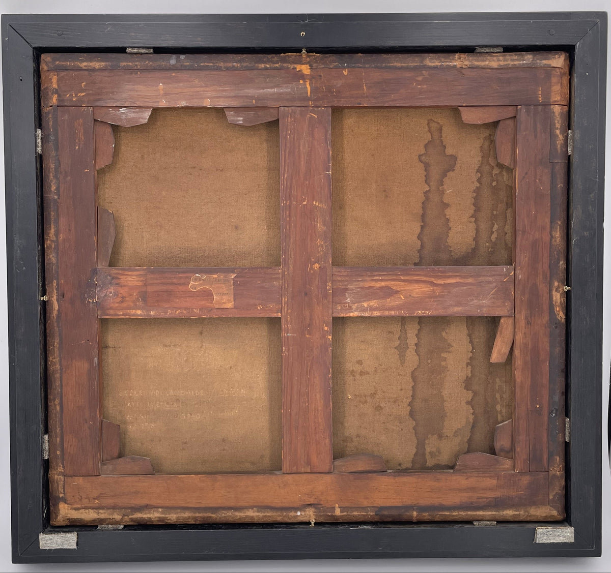 The back of a lined canvas on a cross-braced stretcher with corner keys, a torn paper label and old lettering, in a black frame